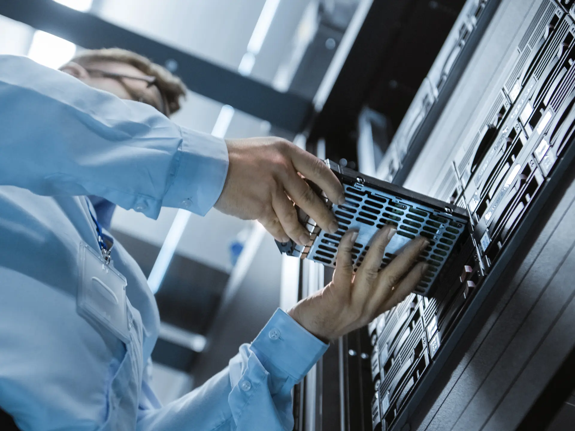 A technician inserting or removing a server component inside a rack, likely performing hardware maintenance or upgrades.