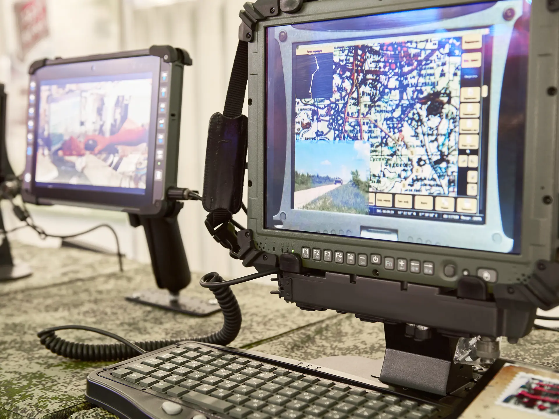 Two rugged tablet-style computers mounted on stands, displaying digital maps and imagery, with a keyboard in front.