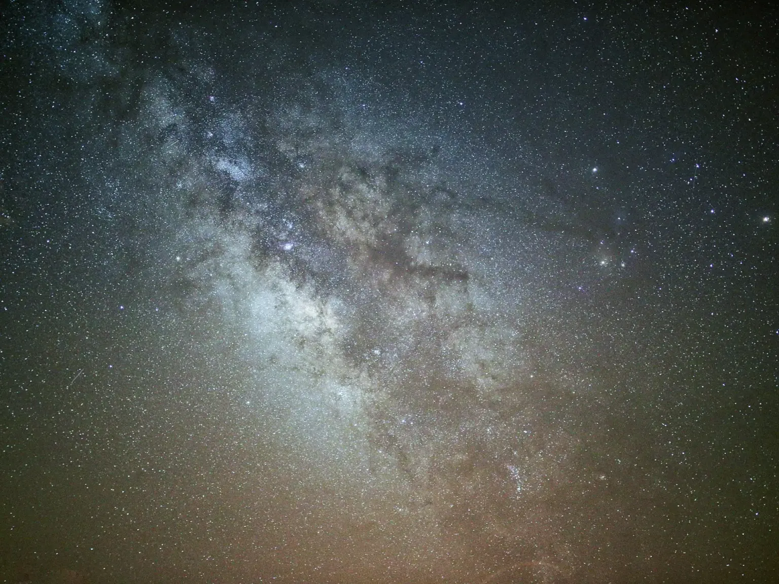 A long-exposure night sky image showing dense star fields and the bright galactic core.