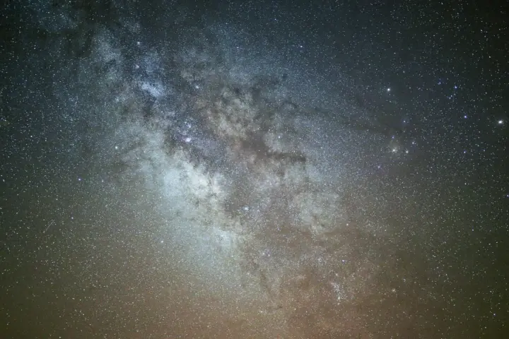 A long-exposure night sky image showing dense star fields and the bright galactic core.