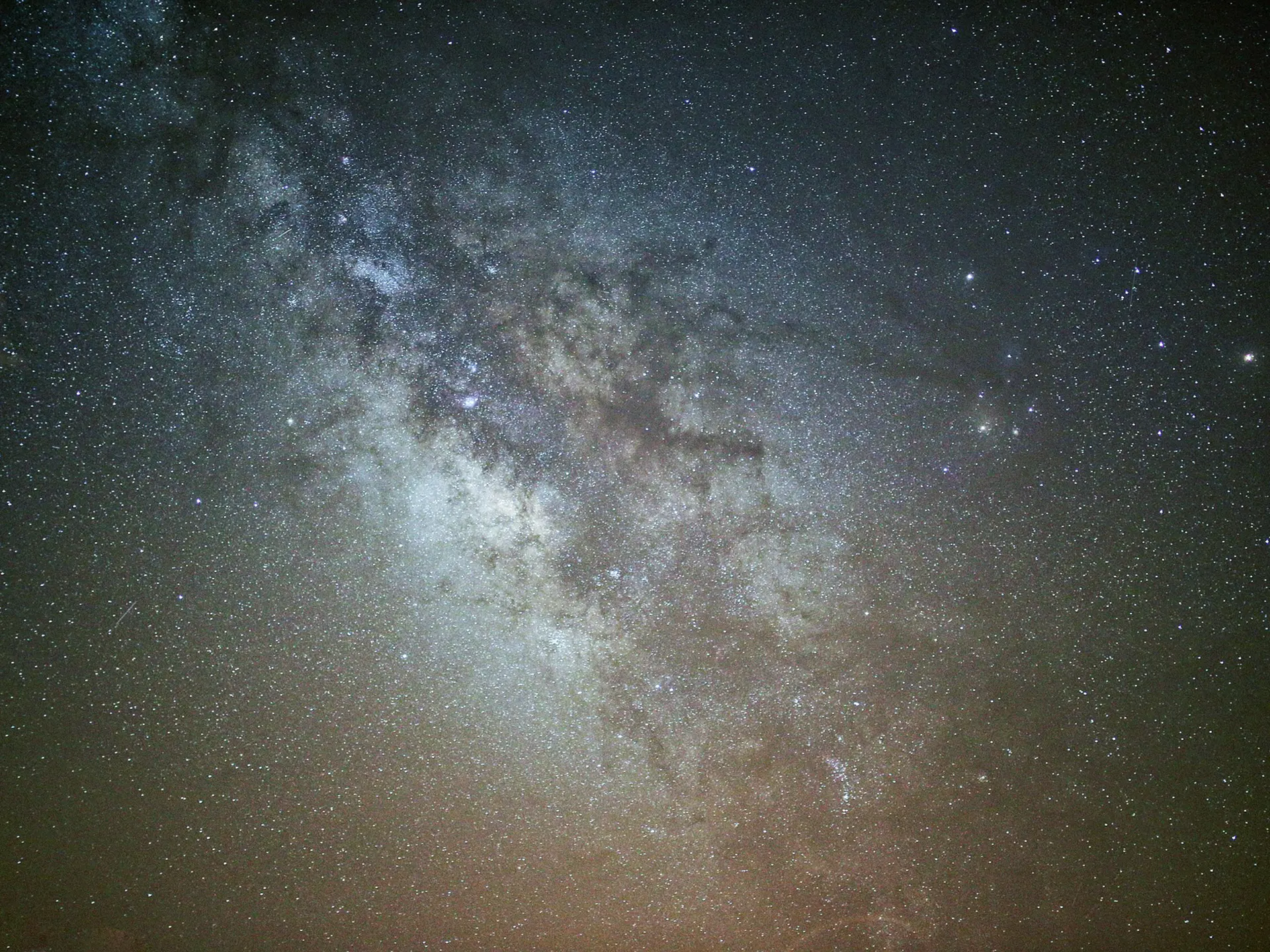 A long-exposure night sky image showing dense star fields and the bright galactic core.
