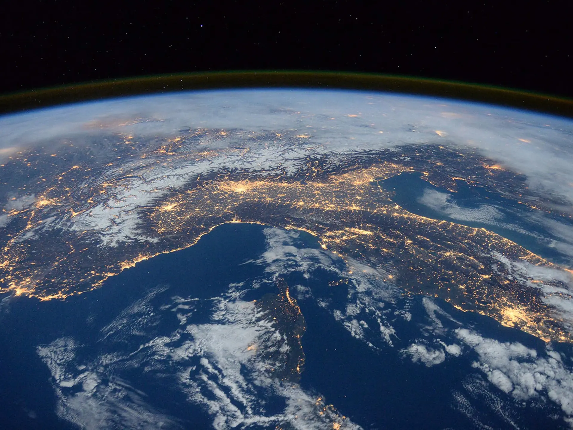 A view of Earth from space with city lights clearly visible, likely showing parts of southern Europe and surrounding areas.